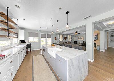 A kitchen with white cabinets and a marble counter top.